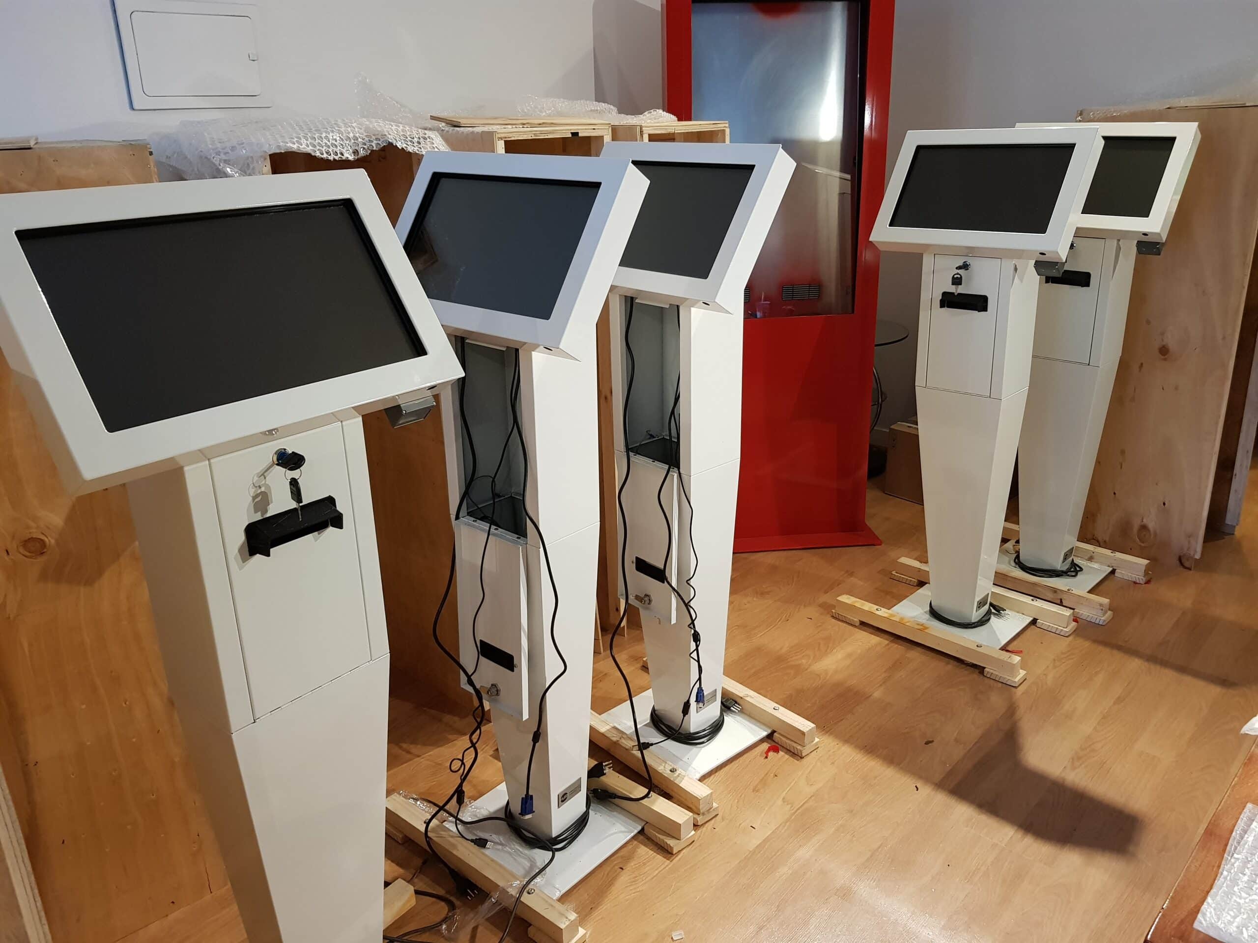Vista frontal de los kioscos interactivos implementados por PLED para Kupfer, con pantalla táctil y sistema de impresión de tickets para turnos