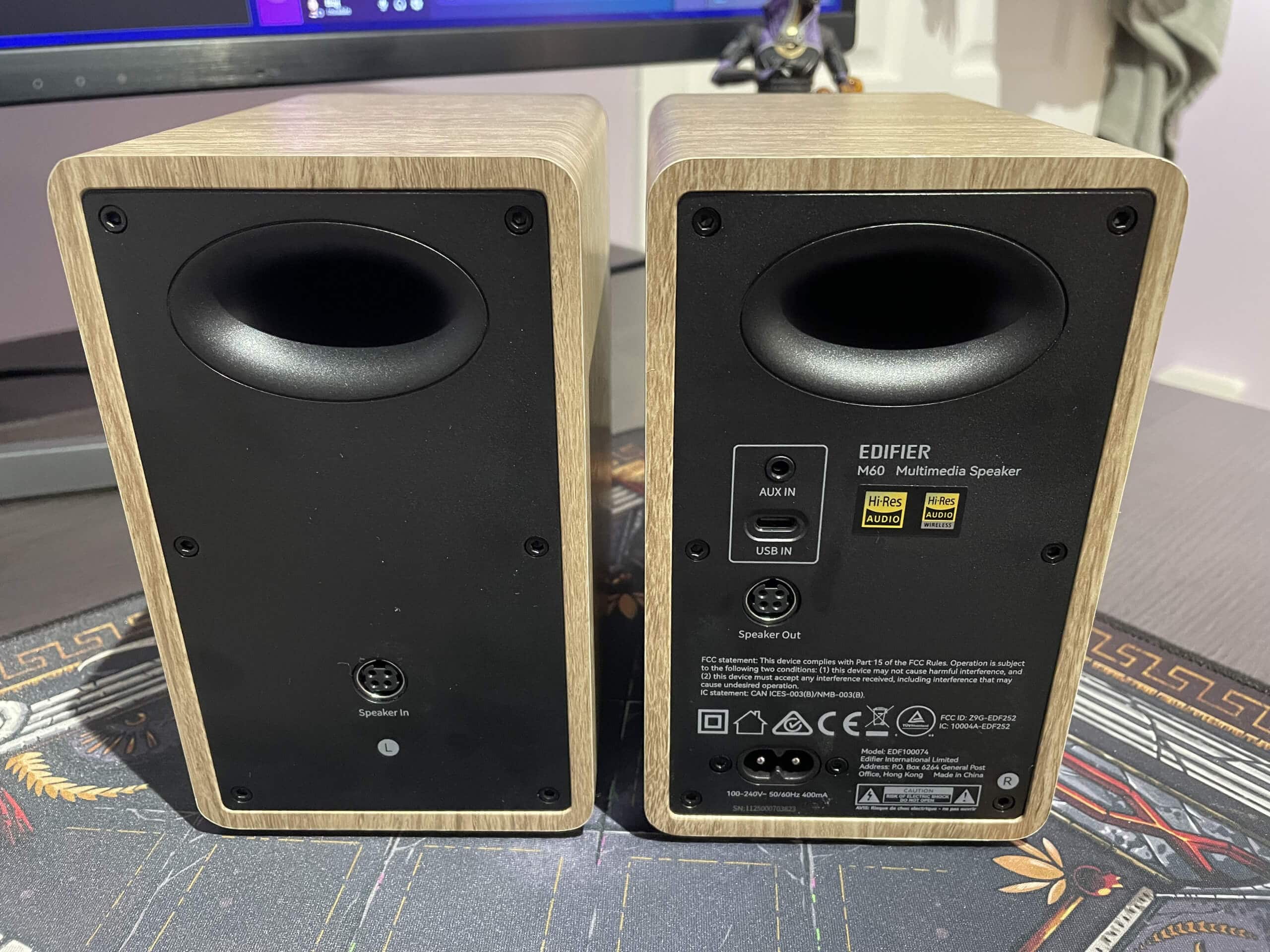 The rear faces of the Edifier M60 speakers. Shows the connection ports for AUX, USB-C, speaker to speaker, and power.