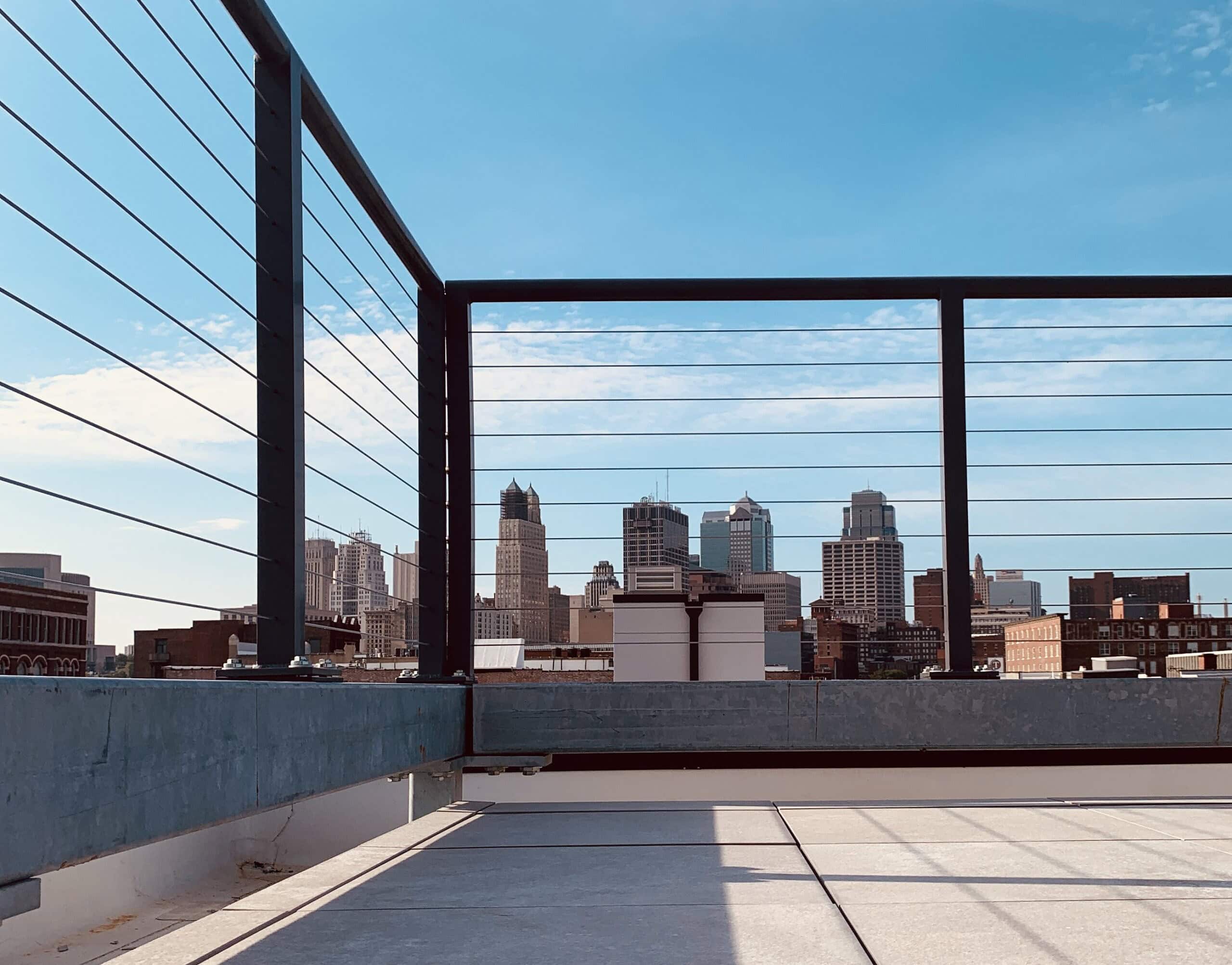 Sturdy cable railing with black framing, with downtown skyscrapers in the background.