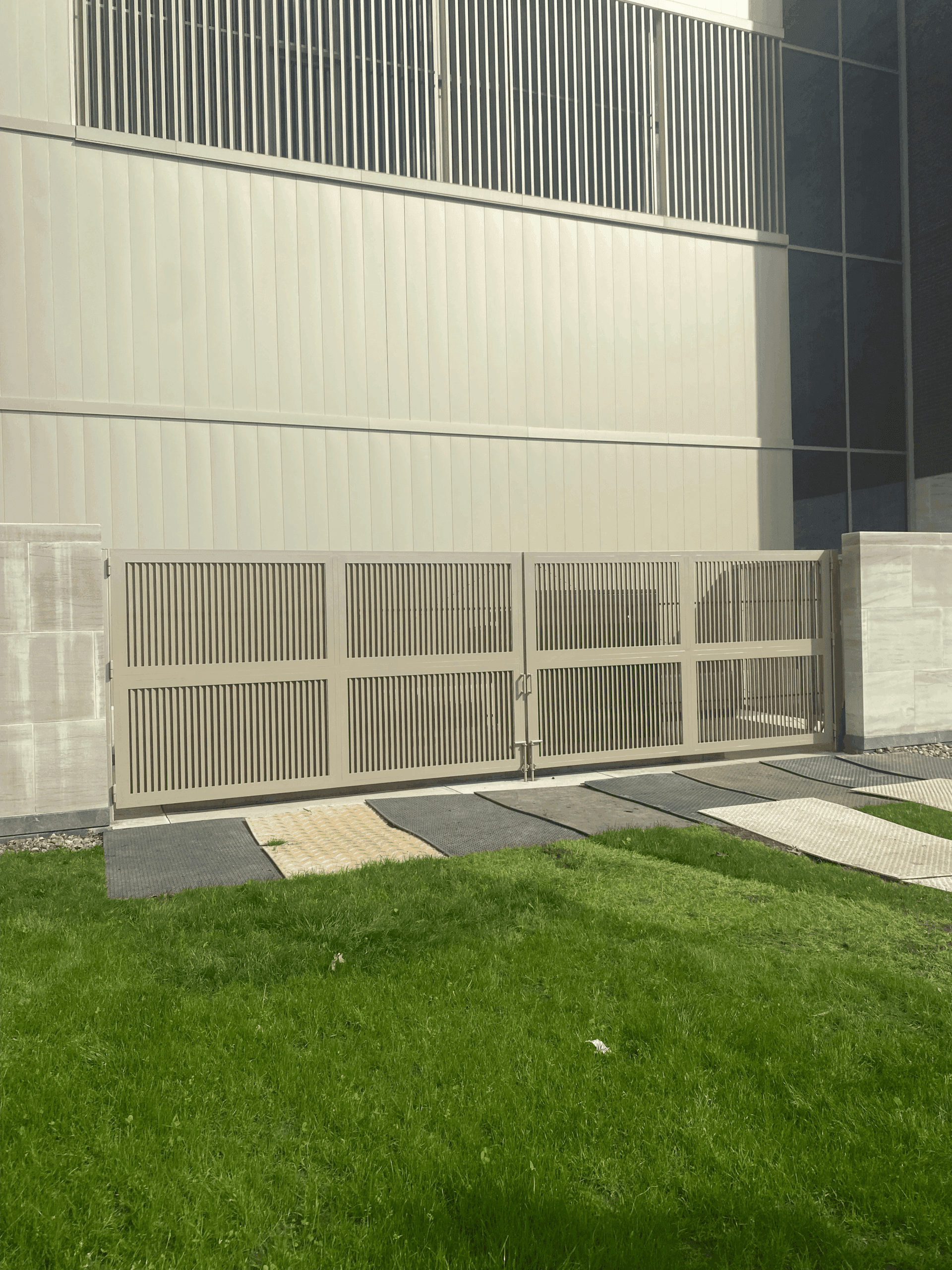 Gray industrial swing gates with vertical louvered infill.