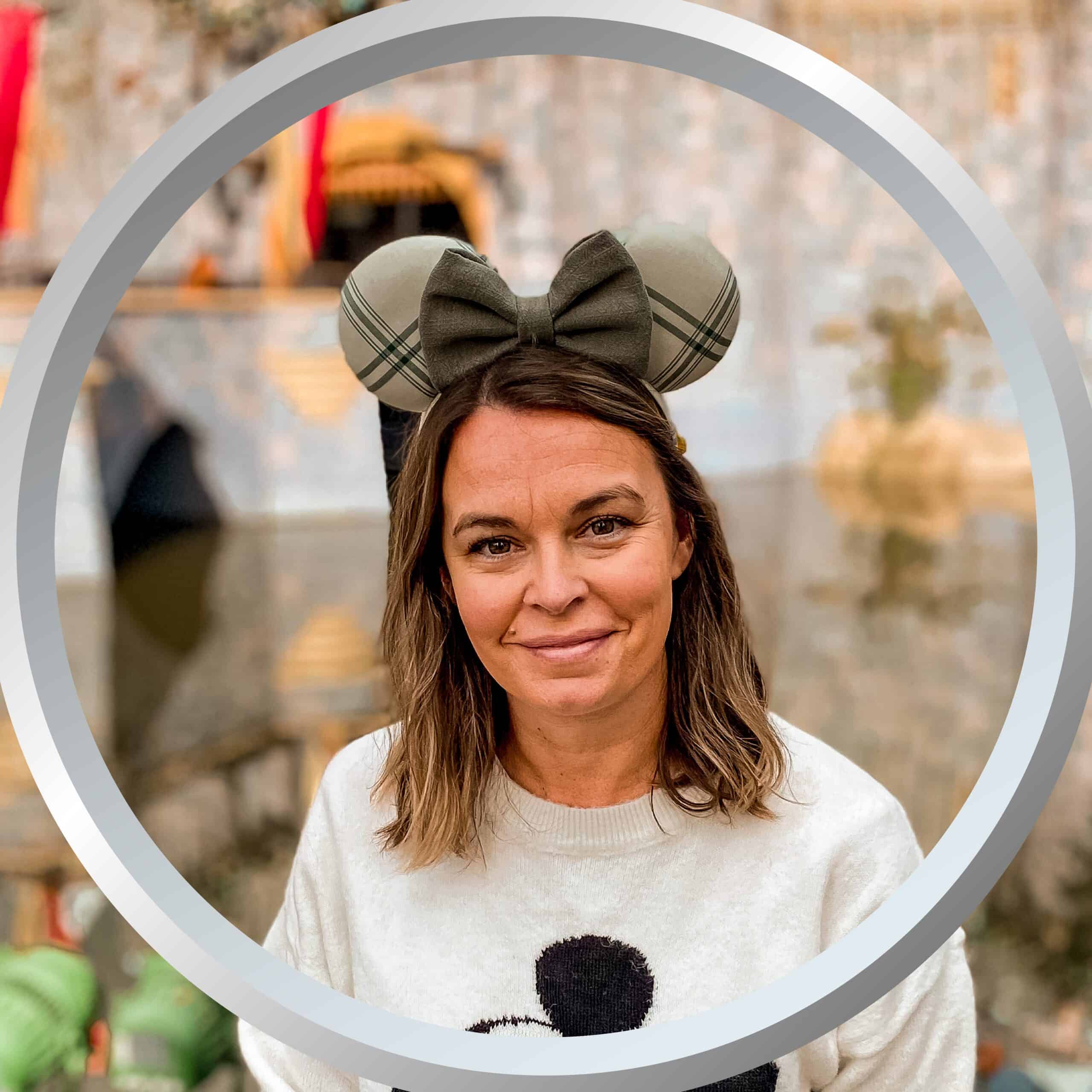 Festive woman wearing Disney-inspired ears at Disney theme park, enjoying her vacation.
