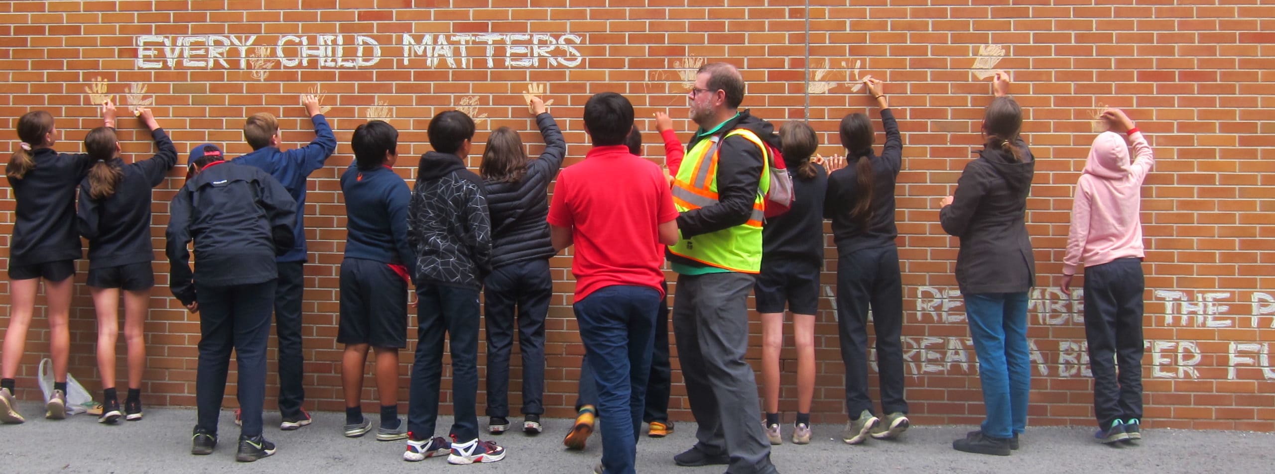 Students putting handprints on a brick wall for Every Child Matters | Bishop Hamilton Montessori School in Ottawa