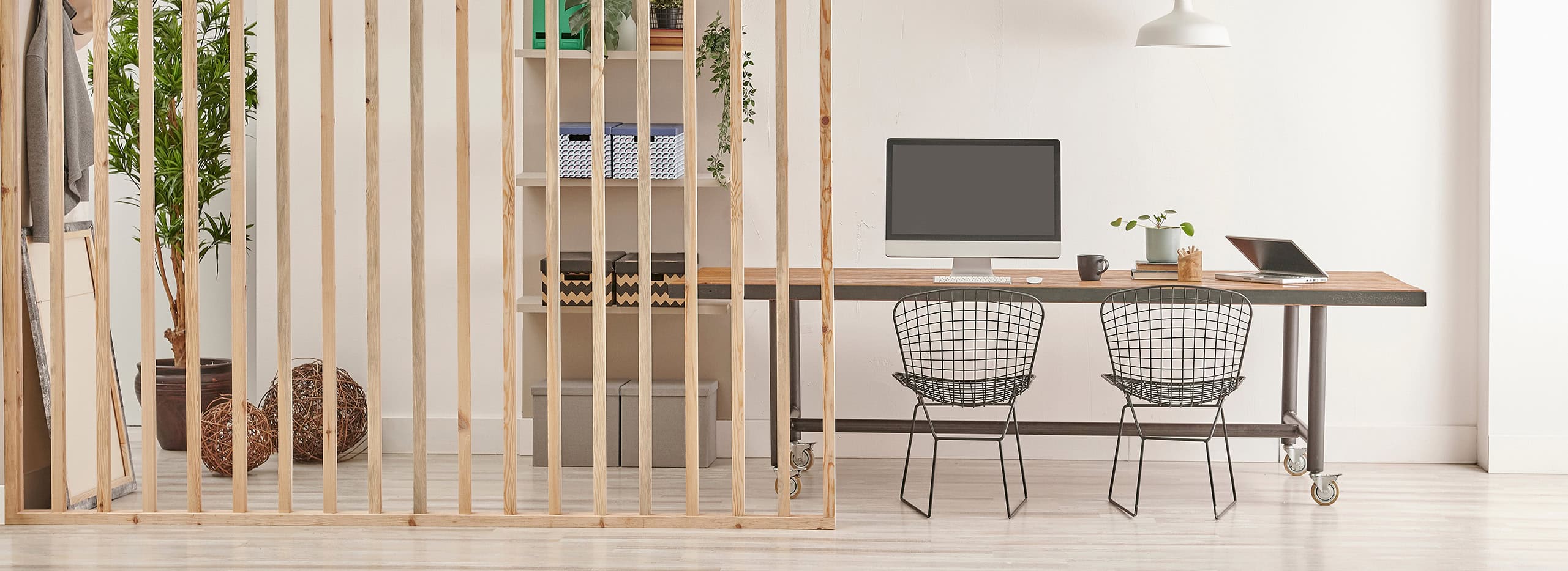 Das Bild zeigt ein modernes, helles Zimmer mit minimalistischer Einrichtung. Im Vordergrund befindet sich eine vertikale Holzlattung, die den Raum teilt. Symbolbild für Raumteiler.