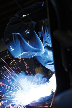 Image of a welder, looking down while welding