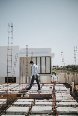 A modern residential building under construction with a person inspecting the site.