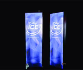 Two vertical commercial lightbox signs featuring a geometric blue diamond pattern background with the text “Dry ICE INTERNATIONAL” prominently displayed in white and light blue colors. Below the main text, there is a website address: “www.dryice.co.za”. The signs are illuminated from within, making them stand out against the dark background. This image highlights how commercial lightbox signs can be used effectively for advertising or branding purposes in various commercial settings.
