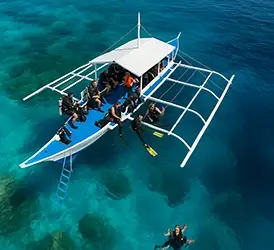 Aerial view of dive boat in crystal clear waters of Bohol, Philippines – the best dive sites in Bohol. An aerial dive boat scene—crystal-clear Bohol waters, eager divers, and enough excitement to make even a sea cucumber jealous!