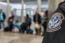 Close-up of Homeland Security uniform with travelers waiting in airport background
