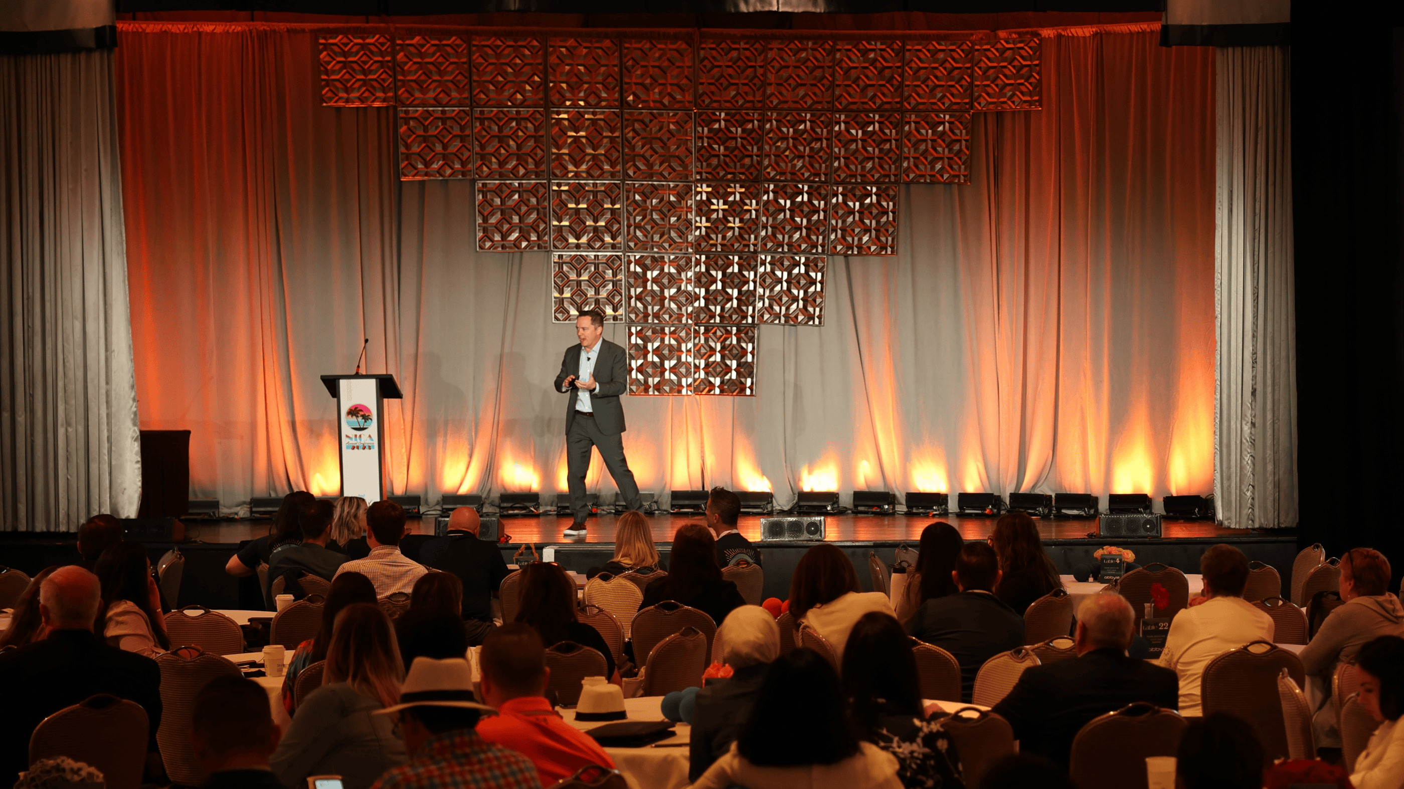 Keynote speaker presenting at the NICA Annual Conference in Miami, organized by CTC, with attendees engaged in the session.