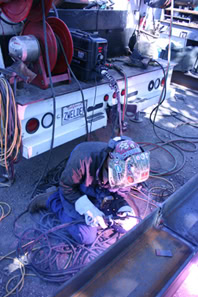 image of a welder in an outdoor, rugged setting