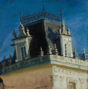 Historic palace outbuilding in Kozienice with ornate baroque roofline against a deep blue evening sky.