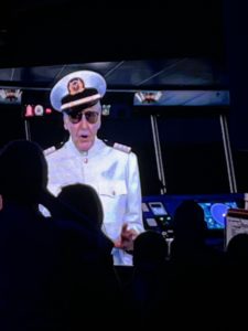 Captain in uniform with sunglasses speaking at an airport or cruise port, symbolizing travel and vacation services.