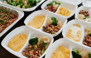 Assorted meal prep containers with beans, broccoli, and mashed potatoes, perfect for healthy eating.