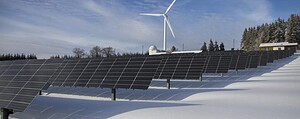 Solar panels and wind turbine in a snowy landscape, showcasing renewable energy sources.