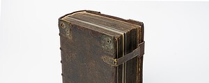 services-01 A detailed studio shot of an antique leather-bound manuscript, showcasing its aged and classic appearance.