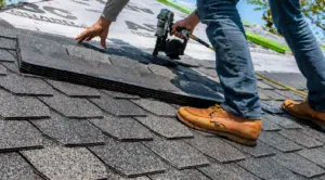 Roofer nailing new asphalt shingles with a nail gun
