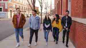 A diverse group of friends walking down the street together, smiling and looking at a phone, symbolizing the importance of community and support through LGBT therapy and LGBTQ+ suicide prevention in Ann Arbor, MI.