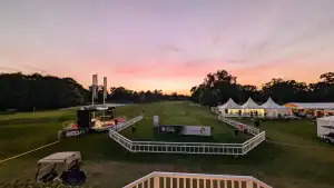 Veranstaltungsgelände auf einem Golfplatz bei Sonnenuntergang mit Zelten, Bühne und Werbebannern