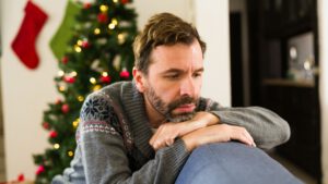 Nachdenkliche Person vor weihnachtlicher Dekoration - Weihnachten und Einsamkeit