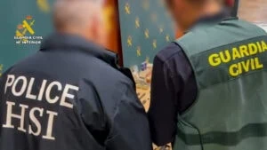 Agentes de la Guardia Civil y la policía observan objetos sobre una mesa, en un entorno de operación policial en Madrid.