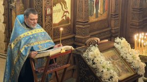 Священник читает перед праздничной иконой Покрова Пресвятой Богородицы