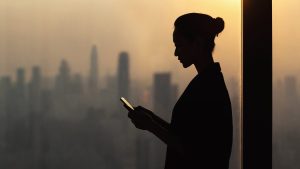 A silhouette of a woman using a tablet in front of a city, contemplating her career purpose and ikigai