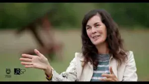 Siobhan Humston, artist in residence, seated outdoors and gesturing while speaking at the Jeffrey Rubinoff Sculpture Park.