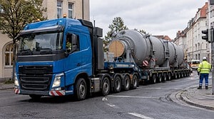 Ein Schwertransport passiert eine Kreuzung im Stadtzentrum