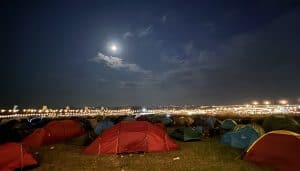 Night-time view across a festival camping site towards the main arena