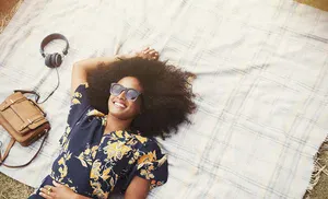 overhead view smiling woman with afro laying on blanket