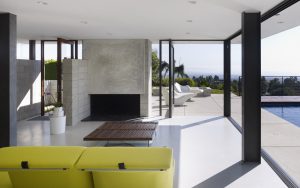 Modern residential living room with floor-to-ceiling glass doors opening to an outdoor pool area.