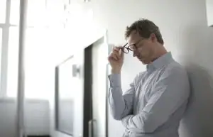 Man with his hand on his head representing work stress, suggesting quiet burnout or emotional numbness; concept for men's counseling in Detroit, MI and counselor for men in Detroit, MI.