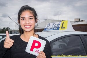Student Monica giving a thumbs up while holding her red P-plate outside D-Tech Driver Training car after passing her driving test.