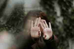 person in brown long sleeve shirt covering face with hand representing symptoms of trauma and how EMDR therapy in Detroit, MI can help.