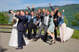Gruppenfoto, das Liebespaar macht ein Selfie mit den Gästen im Hintergrund Ein tolles Gruppenfoto vom Hochzeitsfotograf