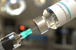 Jeringa cargándose con una dosis de vacuna desde un vial, en un entorno clínico