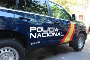 Vehículo de la Policía Nacional estacionado en una vía pública, mostrando su distintivo y colores policiales, con árboles vis