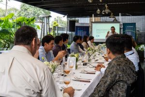 Asistentes sentados en mesa larga durante una charla corporativa con proyección de diapositivas en La Vaca Loca