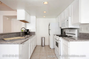 Bright kitchen at 4205 Ohio Street featuring clean white cabinetry, granite countertops, a gas range with an overhead microwave, and neutral tile flooring.