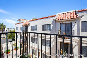 View from a private balcony at 4205 Ohio Street overlooking a Mediterranean-style residential complex with white stucco walls, red clay tile roofs, and black metal railings under a clear blue sky.