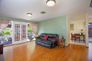 Open living area at 3727 Suffolk Drive in Rolando Park featuring hardwood floors, sage green walls, and large French doors leading to an outdoor patio.