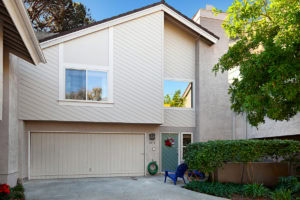 Townhouse exterior at 5474 Caminito Borde in Mission Valley featuring neutral siding, a two-car garage, and a gated patio entryway.
