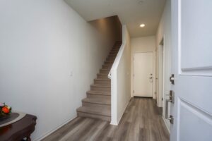 Bright interior entryway of 5235 Beachfront Cove Unit 102 featuring wood-style flooring and carpeted stairs