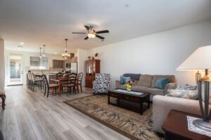 Open-concept great room and dining area at 5235 Beachfront Cove Unit 102 featuring wood-style flooring, designer lighting, and a view into the modern kitchen at Playa Del Sol.