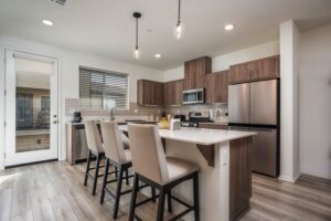 Modern kitchen at 5235 Beachfront Cove Unit 102 featuring a large island, stainless steel appliances, new tile backsplash, and upgraded pendant lighting in Playa Del Sol.