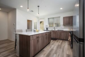 Urban-inspired modern kitchen at 5235 Beachfront Cove Unit 102 showcasing a spacious island with seating, walk-in pantry access, and wood-style flooring.