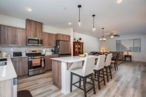 Open-concept second floor at 5235 Beachfront Cove Unit 102 with a luxury kitchen, large island, and seamless flow into the dining and living room area