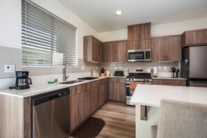 Upgraded kitchen at 5235 Beachfront Cove Unit 102 featuring a NEW tile backsplash, under-cabinet lighting, and maintained modern finishes.