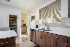 Kitchen view at 5235 Beachfront Cove Unit 102 showing the walk-in pantry, sink, and custom vinyl blinds.