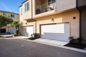 Exterior view of the attached 2-car garage and second-floor balcony with café-style furniture at 5235 Beachfront Cove Unit 102 in the gated Playa Del Sol community.